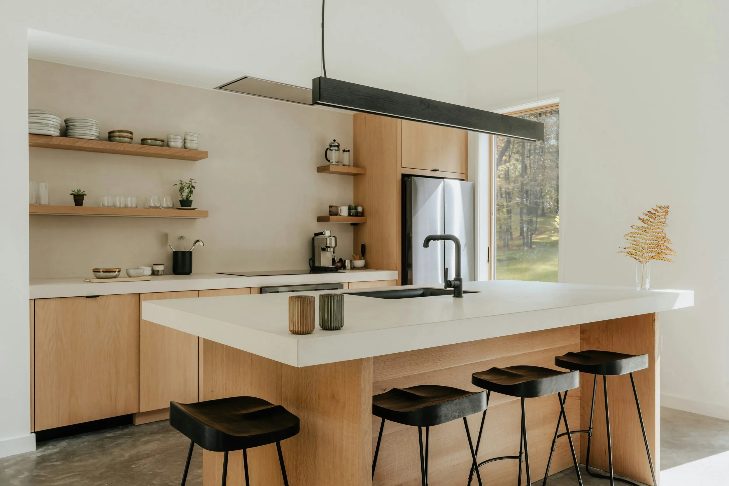 New kitchen with a white stone island bench, oak cabinetry, black bar stools and open timber shelving